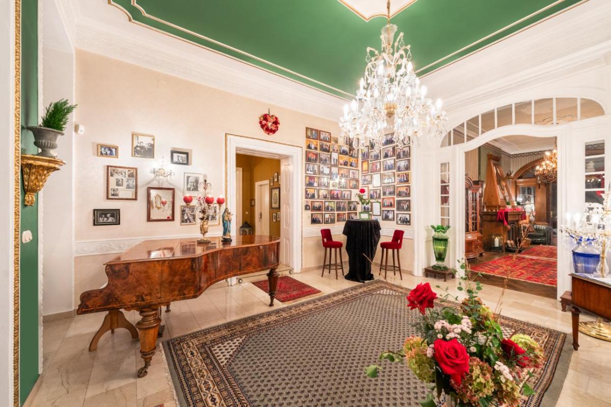 Piano room with a chandelier, a large rug, and pictures on the wall.