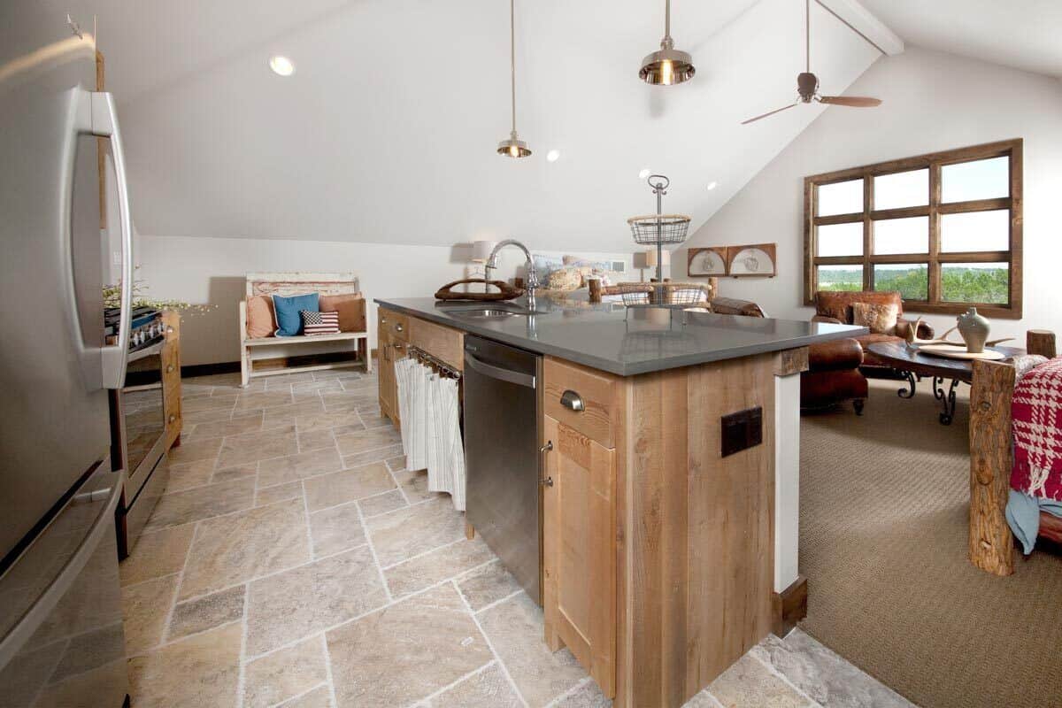 Kitchen with stainless steel appliances and a prep island over the limestone flooring.