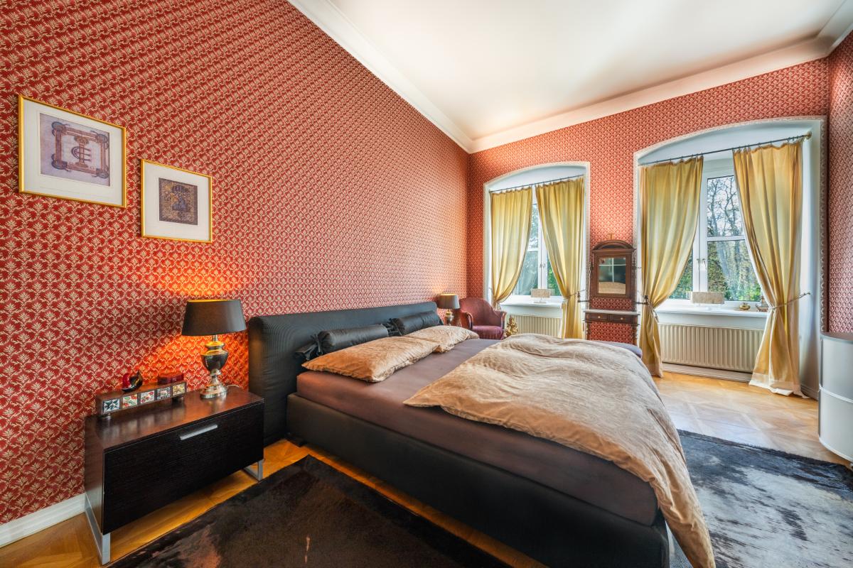 Bedroom with a large bed, glass windows and a large rug.