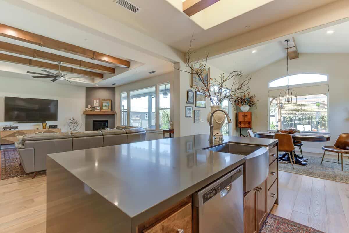Kitchen island with a farmhouse sink and dishwasher overlooking the great room.