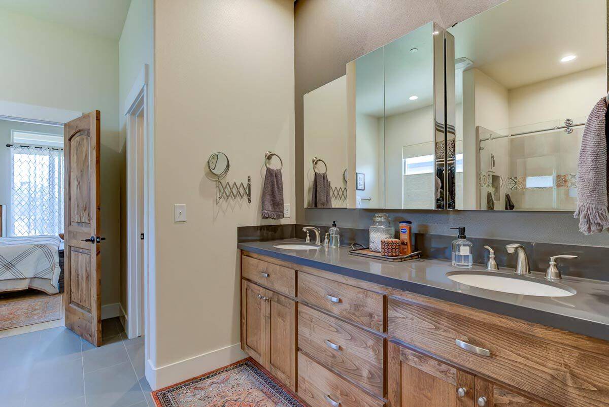 Primary vanity with two sinks, wooden cabinets, and a rectangular mirror.