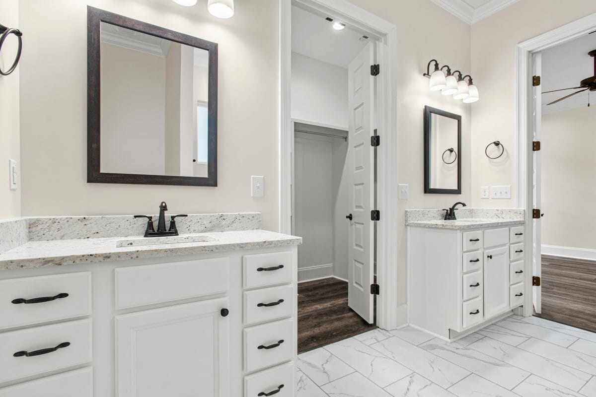 His and her vanities with marble counters and framed mirrors.