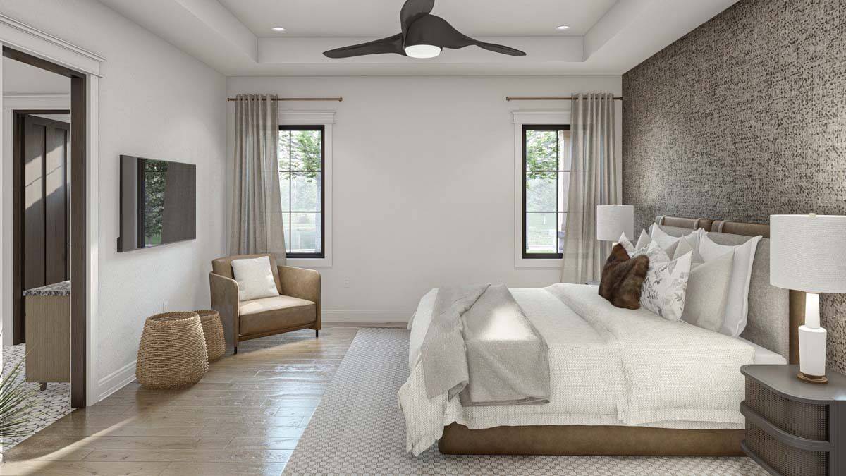 Primary bedroom with a wooden bed, an upholstered chair, and an iron fan mounted on the tray ceiling.