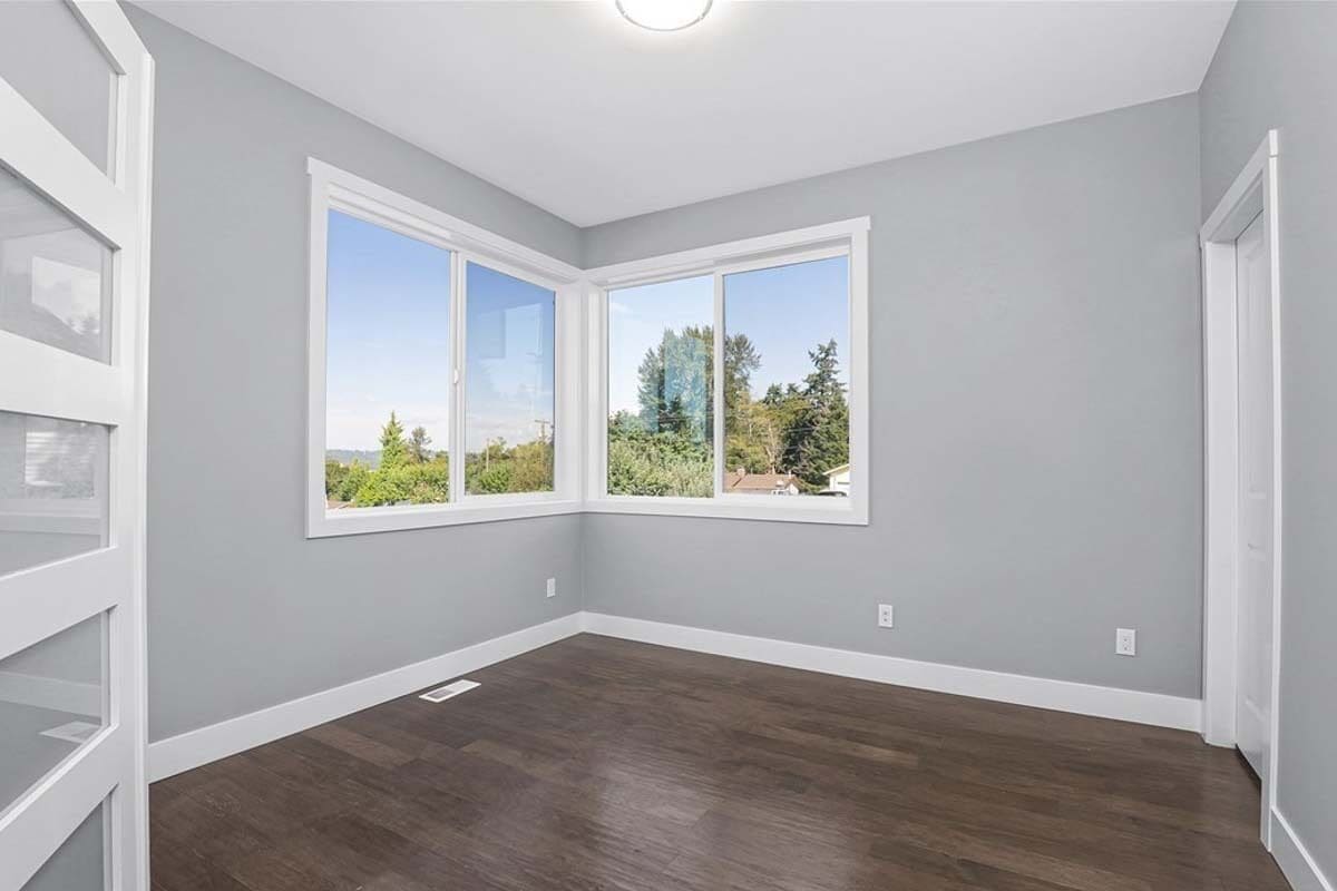 Flex room with sliding windows, a hardwood floor, and gray walls lined with base moldings.