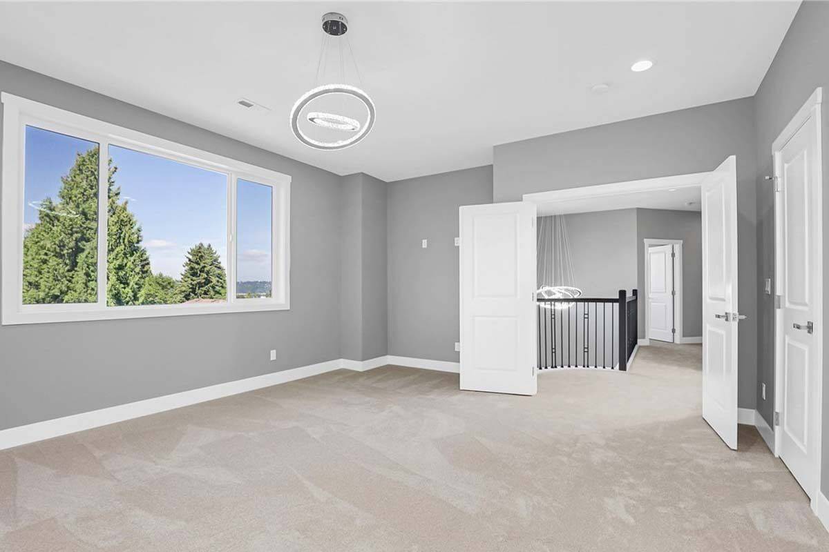Primary bedroom with double doors, a carpeted floor, and a huge window.