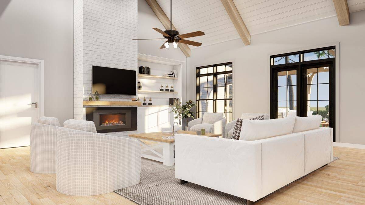 Great room with modern seats, a fireplace with a TV on top, and a cathedral ceiling highlighted by exposed wood beams.