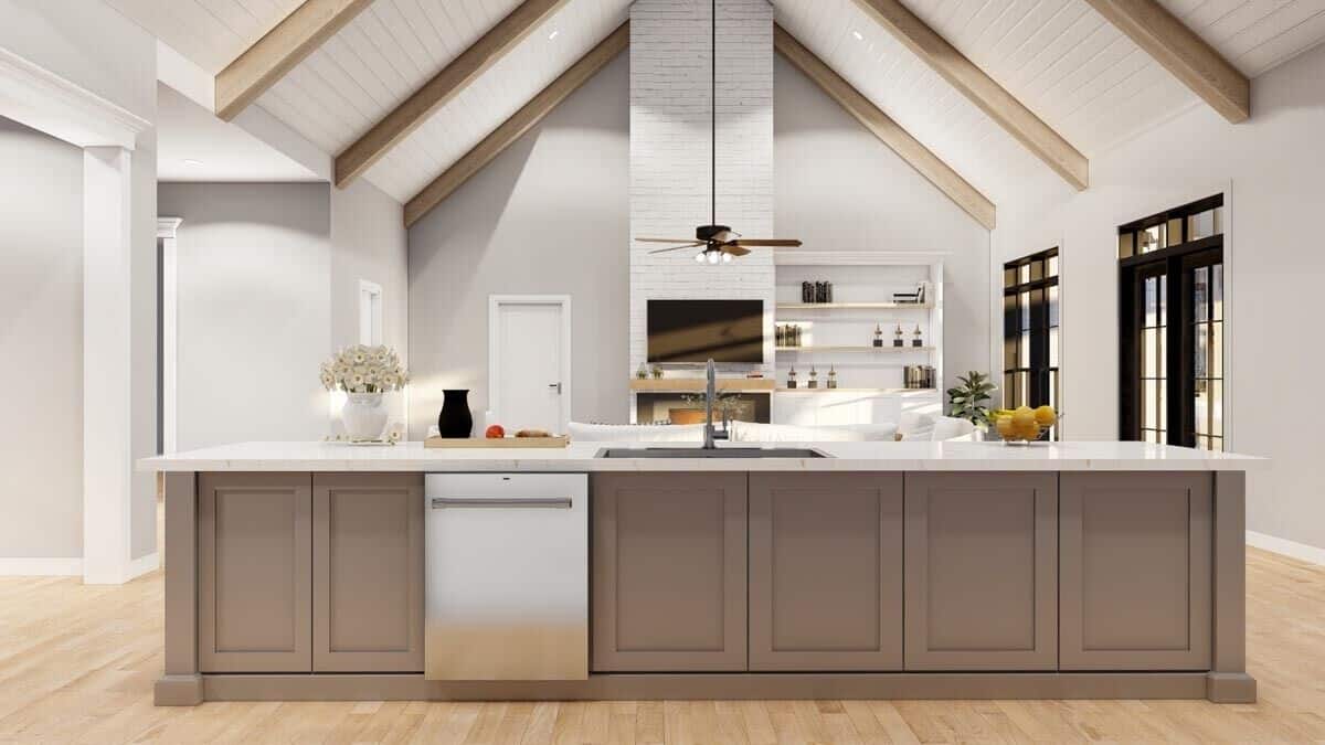 Kitchen island with a sink and dishwasher overlooking the great room.