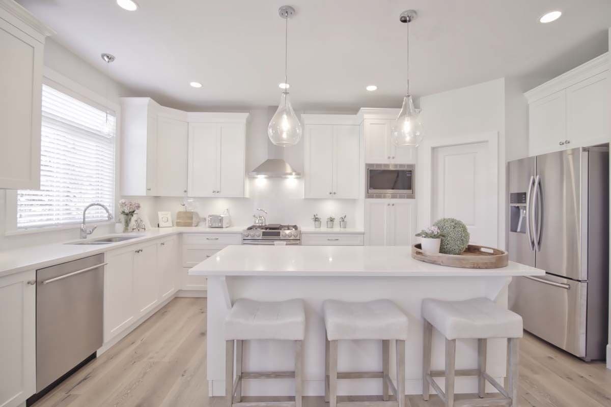Kitchen with white cabinets, stainless steel appliances, and a center island with seating for three.