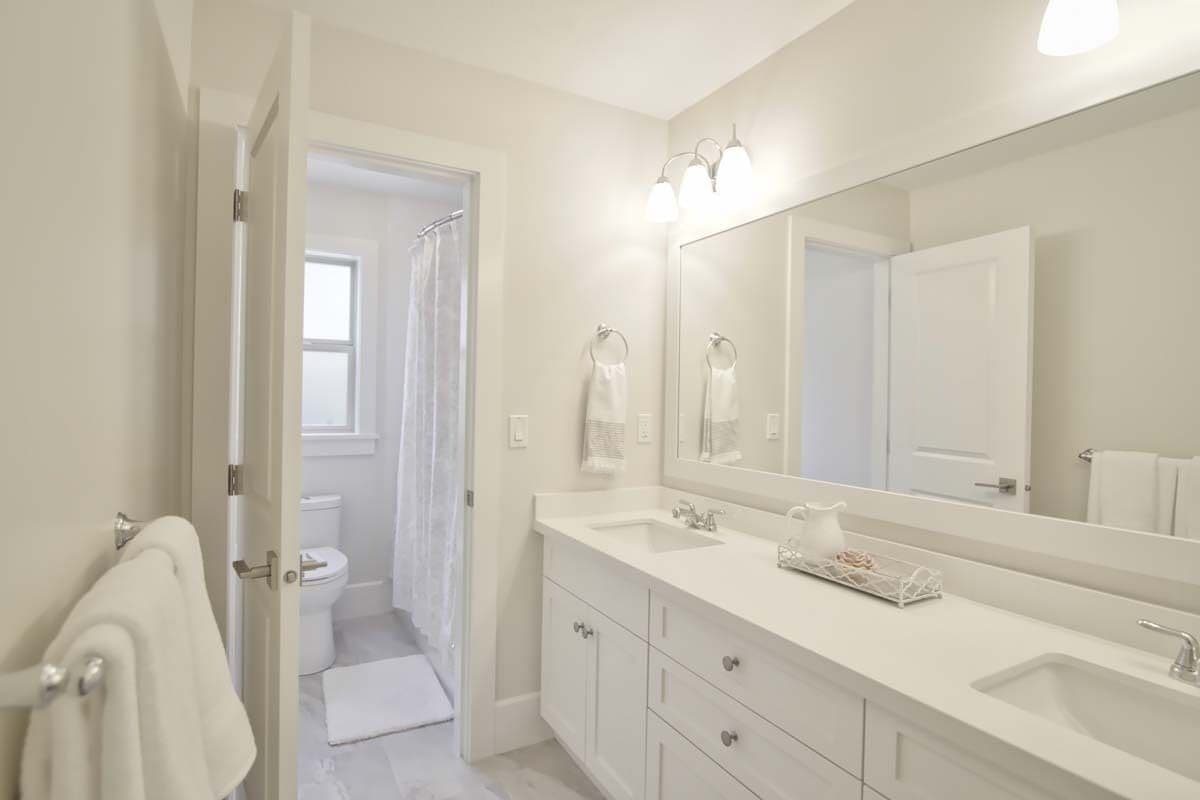 Bathroom with a toilet room and a white vanity with two sinks.