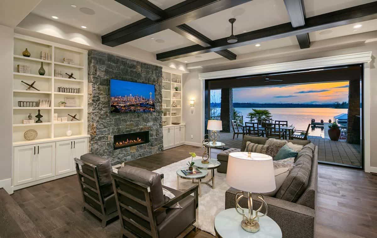 Great room with a coffered ceiling and a stone fireplace flanked by white built-ins.