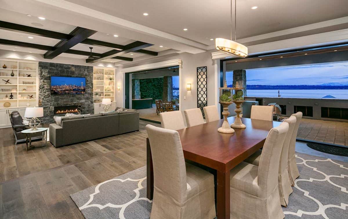 Dining room with a patterned area rug and a wooden table surrounded by high back chairs.
