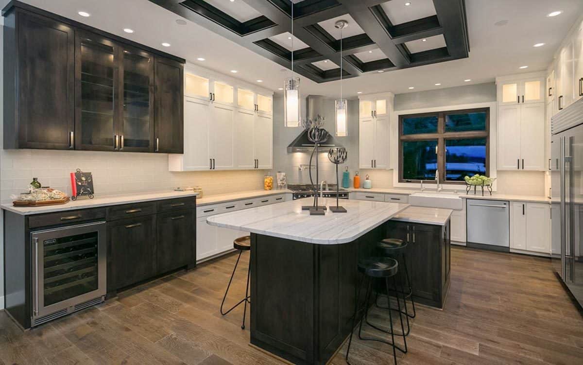 Kitchen with contrasting cabinets, a wine fridge, and a center island topped with cylindrical pendants.