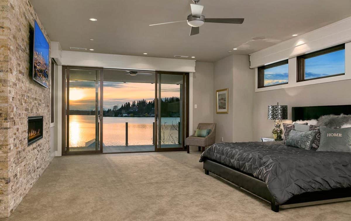 Primary bedroom with a stone fireplace and a leather upholstered bed topped with clerestory windows.