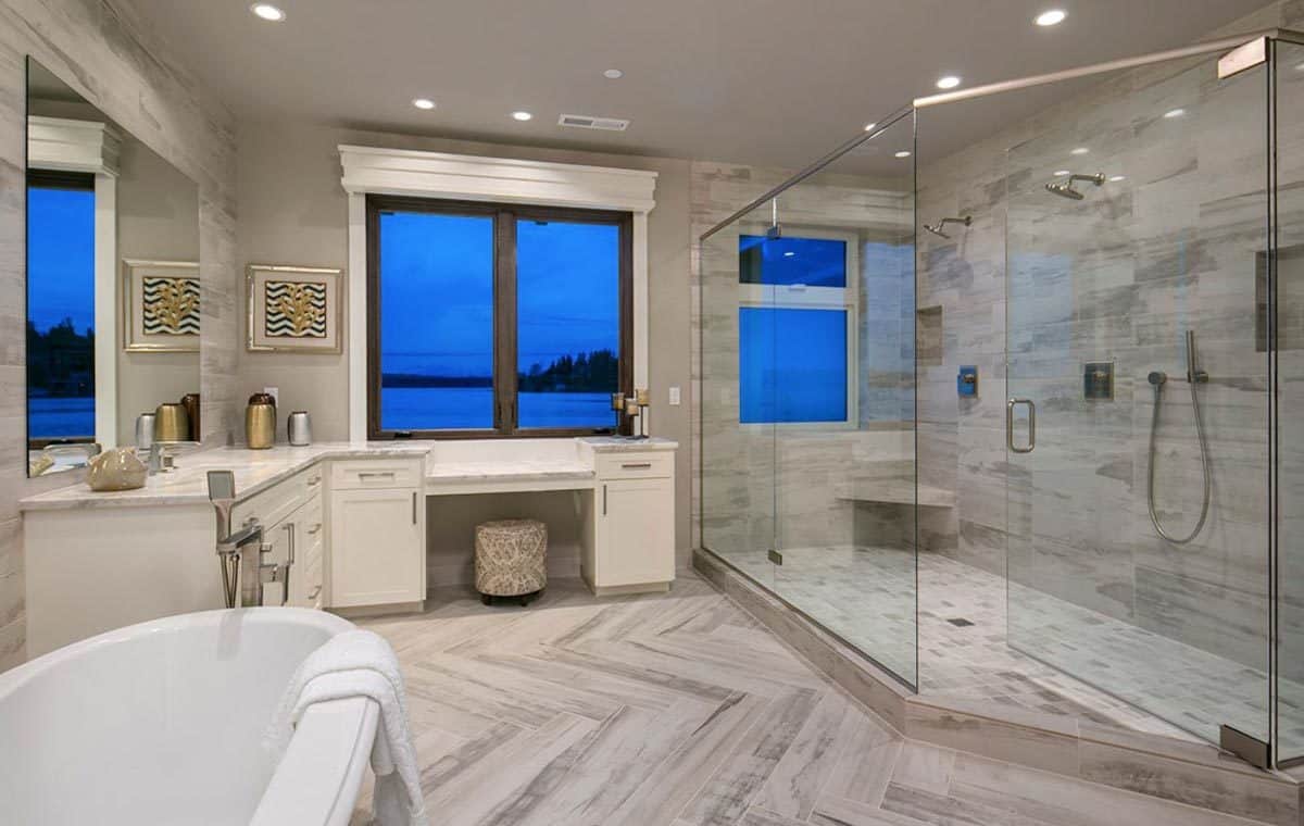 Primary bathroom with a soaking tub, a glass-enclosed shower, and a white vanity integrated with a makeup counter.
