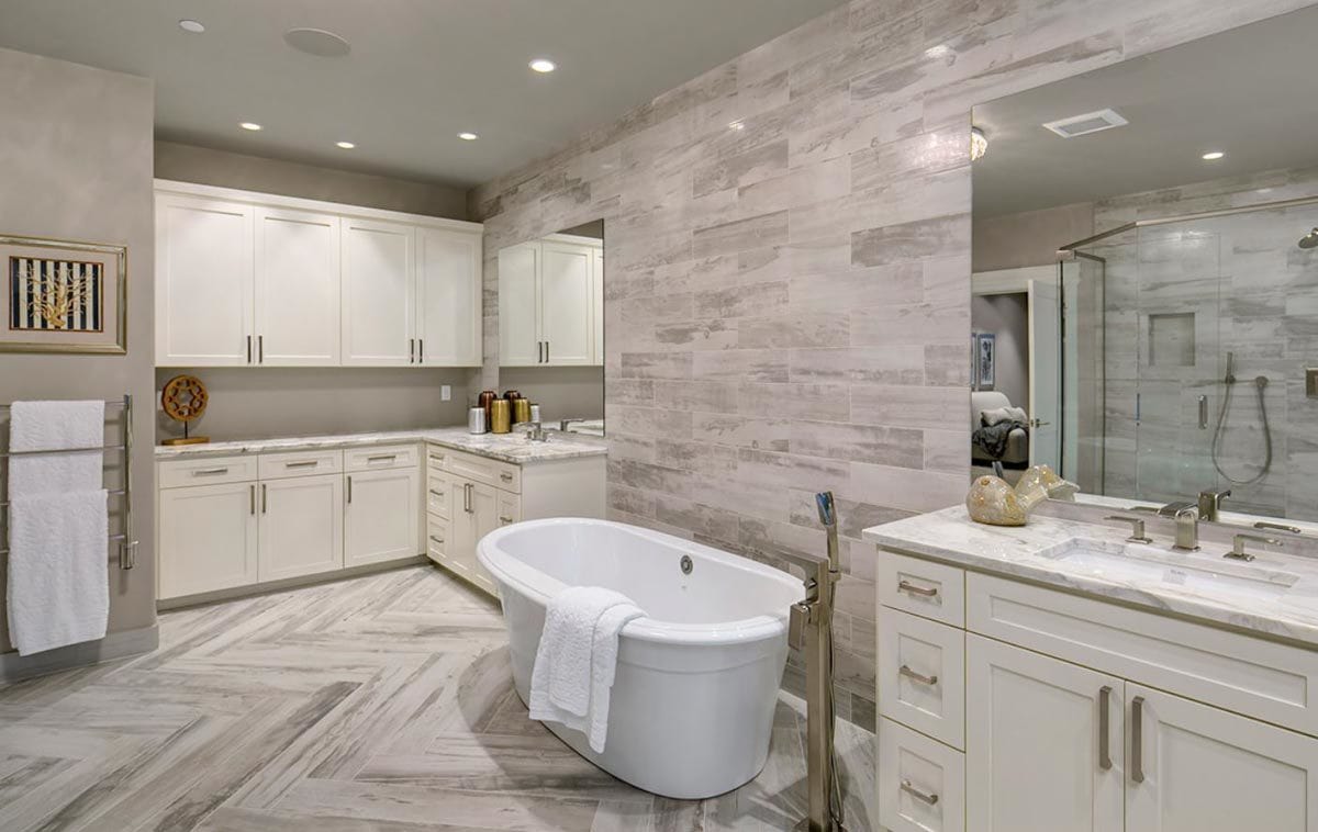 The primary bathroom includes white cabinets and marble tiled flooring arranged in a chevron pattern.