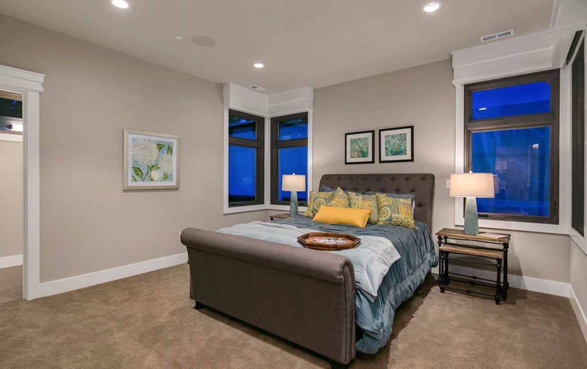 Secondary bedroom with a tufted bed flanked by corner windows.