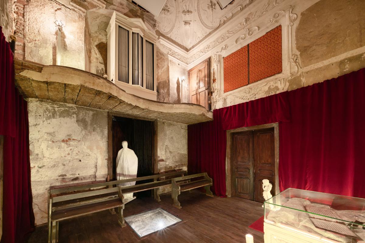 Chapel with statues, long bench seats and wooden doors.