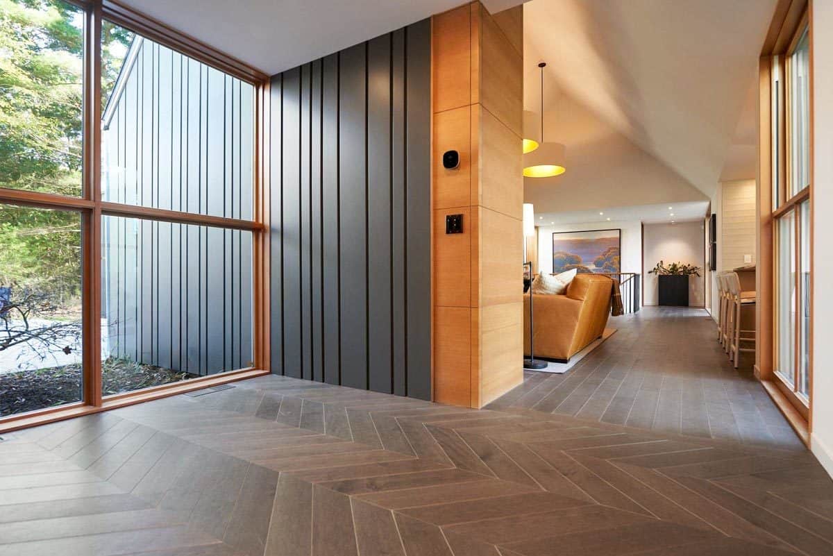Foyer with floor-to-ceiling windows and a hardwood floor arranged in a chevron pattern.