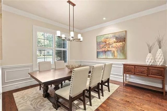 Dining room with a wooden buffet table and a dark wood dining set sitting on a patterned area rug.