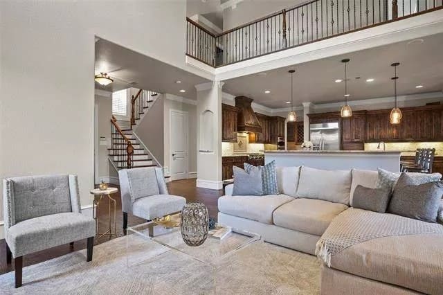 Family room with an L-shaped sectional, tufted chairs, and a glass coffee table over a distressed area rug.