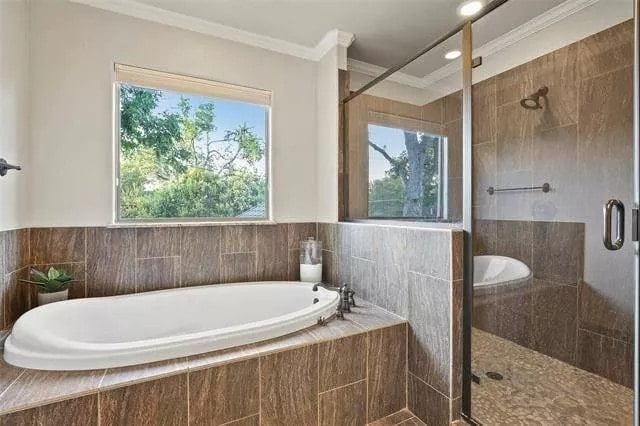 Primary bathroom with a walk-in shower and a drop-in bathtub illuminated by a picture window.