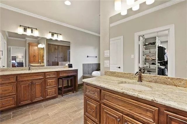 His and her vanities with wooden cabinets, granite countertops, and frameless mirrors.