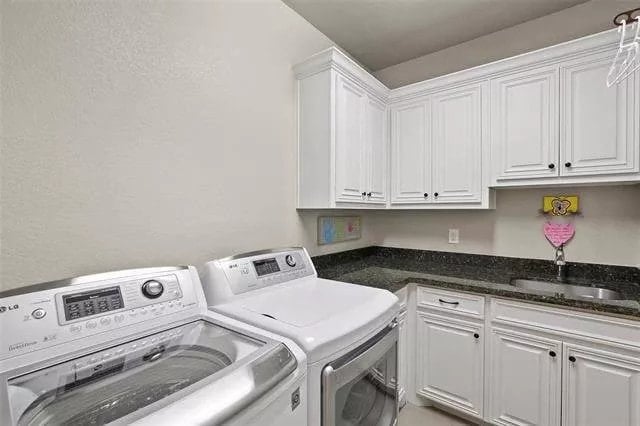 Laundry room with white cabinets, contrasting countertops, and a sink.