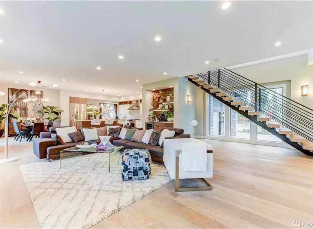 Great room with an L-shaped sofa, a modern armchair, and a glass coffee table over a shaggy area rug.