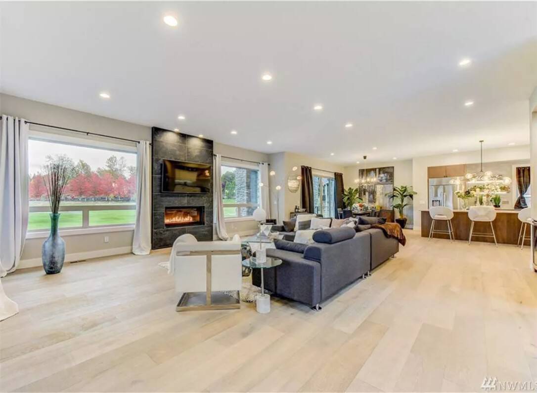 The great room includes a stone fireplace flanked by huge windows.