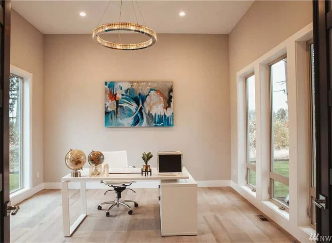 Home office with a white desk and tall windows that invite natural light in.