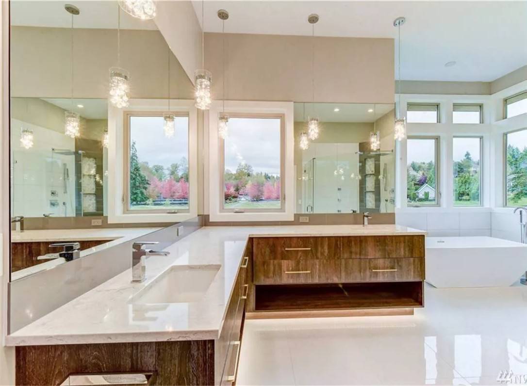 Primary bathroom with his and her vanities and a soaking tub brightened by picture windows.