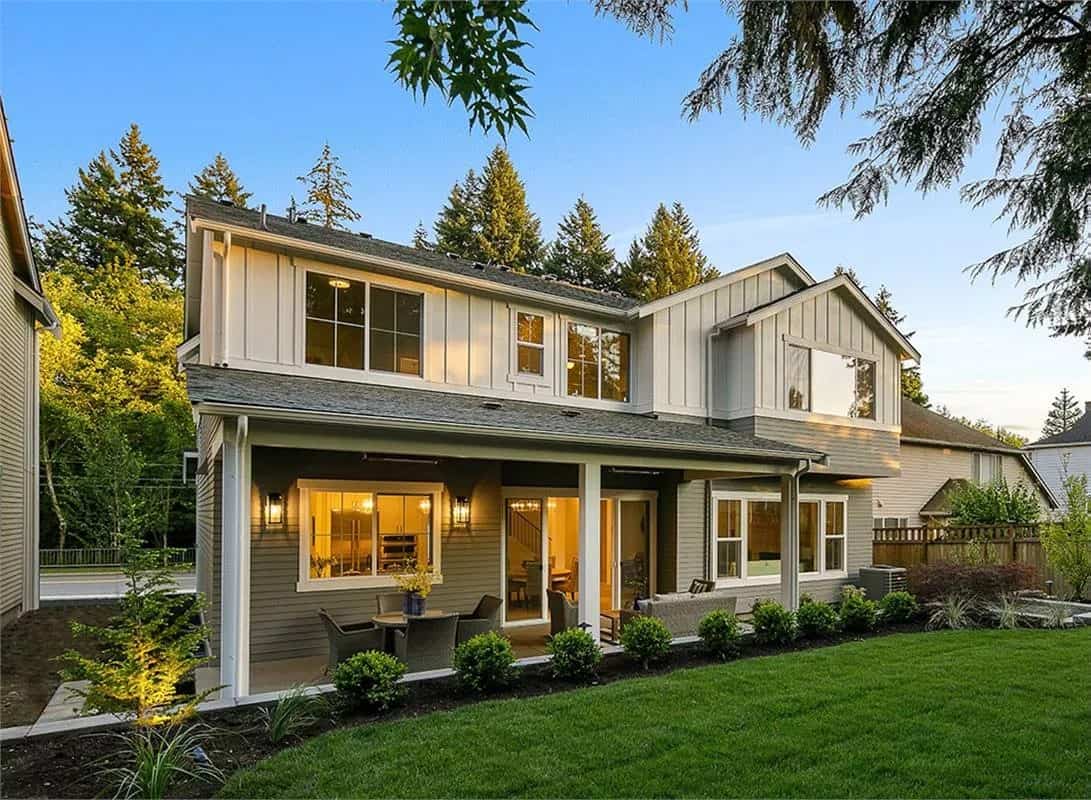 Rear view of the house with a sliding glass doors, abundant windows, and a covered deck.