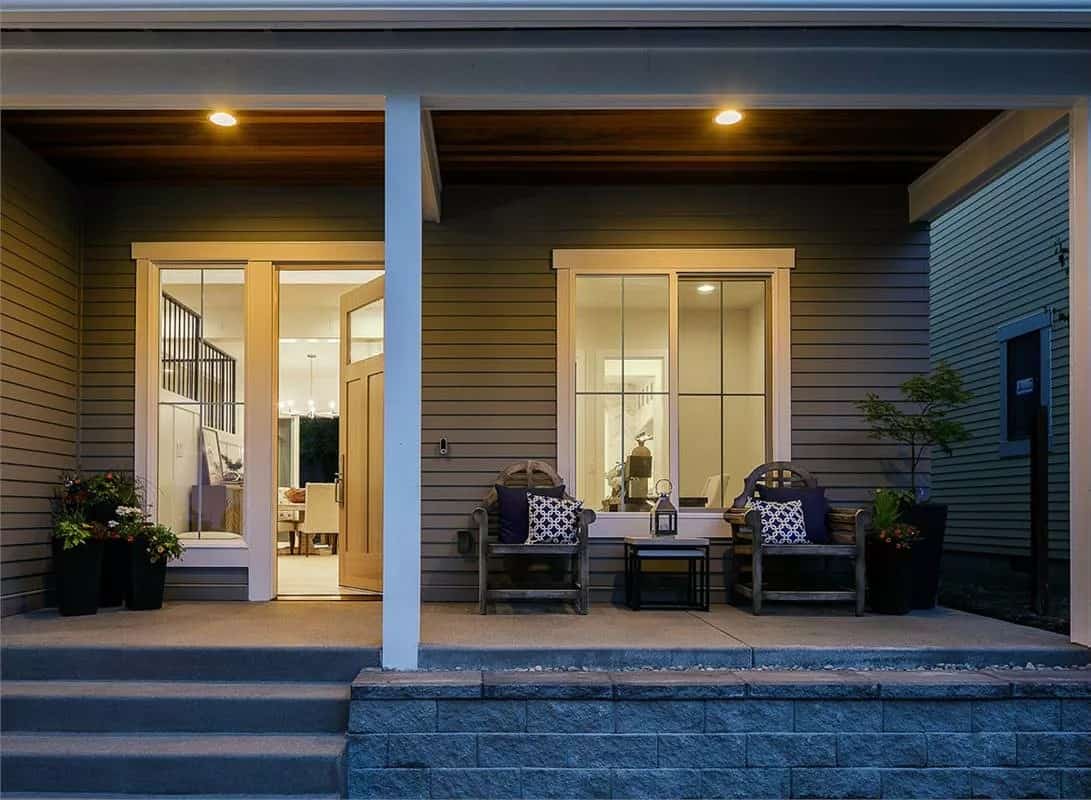 Entry porch with wooden chairs, white-framed windows, and a glazed front door.