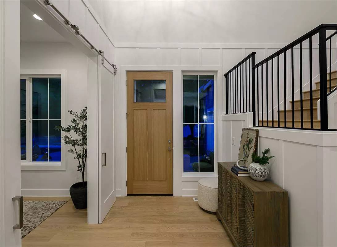 Foyer with a glazed entry door and a wooden console table against the staircase.
