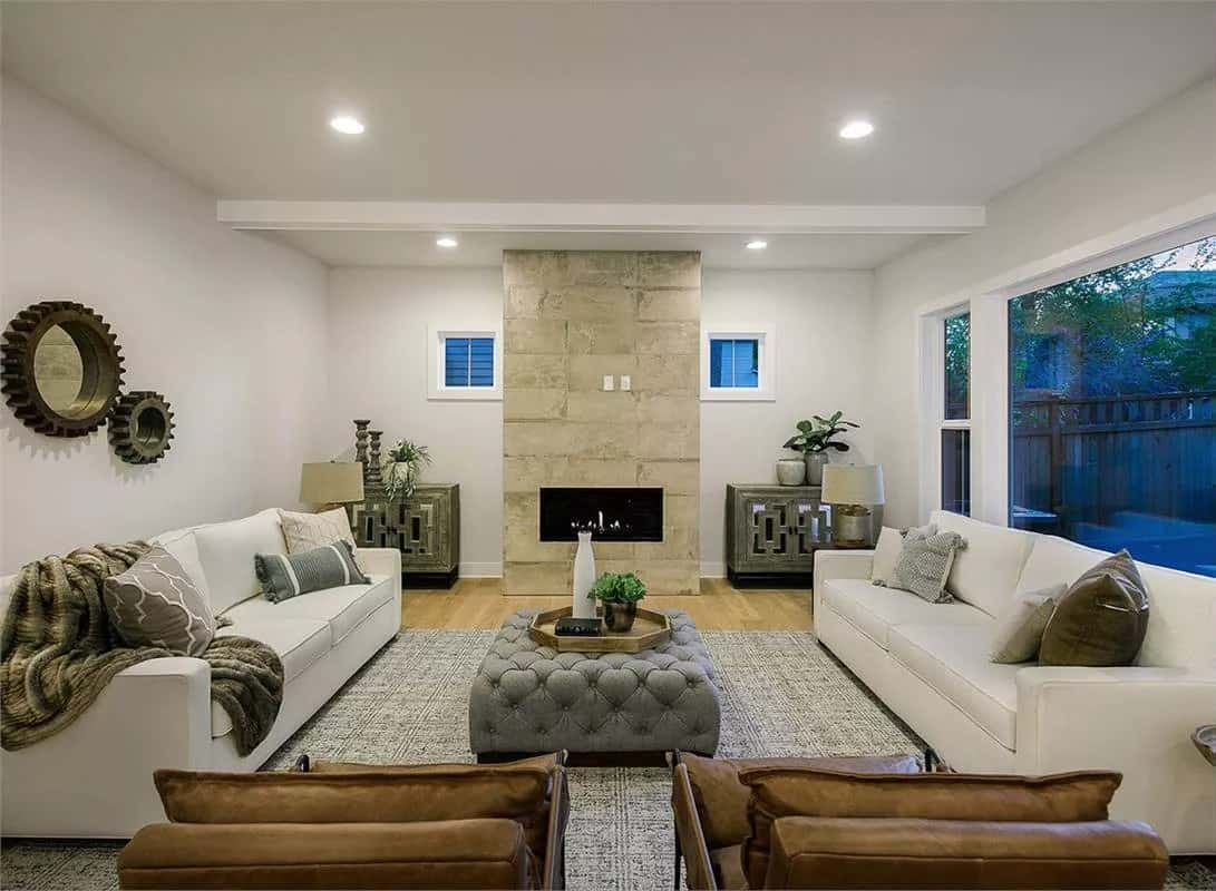 Great room with facing sofas, a tufted ottoman, and a fireplace flanked by base cabinets.