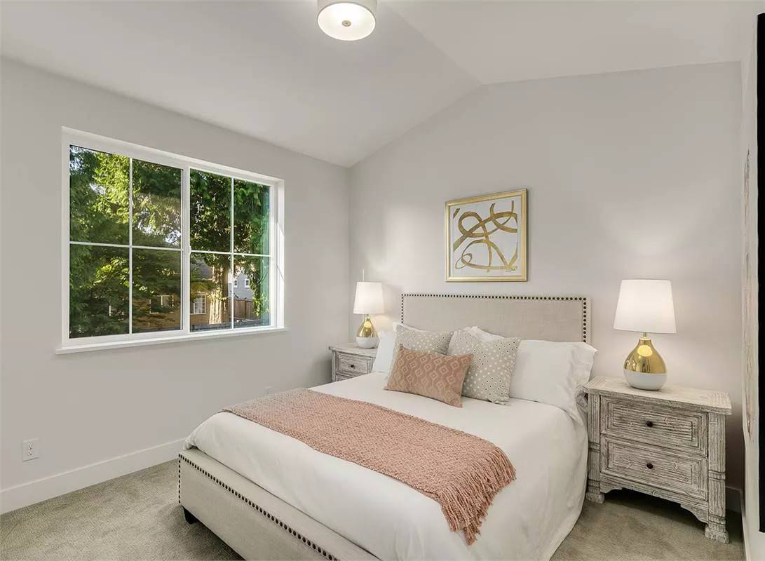 Bedroom with a vaulted ceiling and an upholstered bed flanked by distressed nightstands.