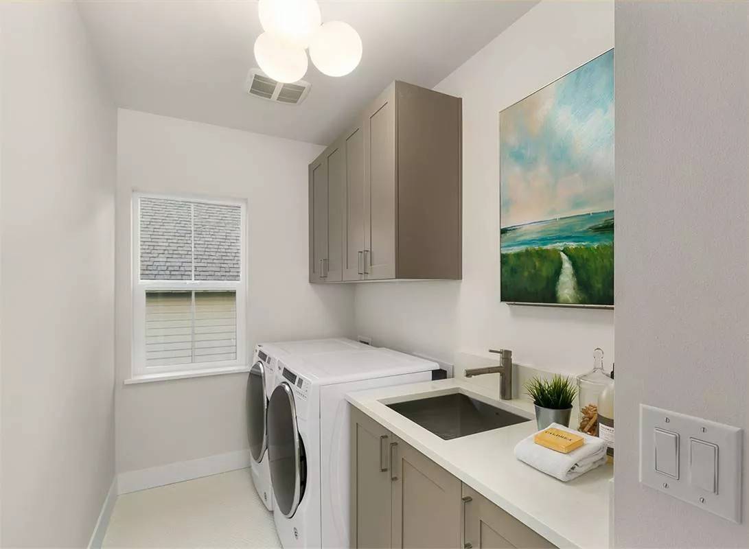 Laundry room with wooden cabinets, front-load appliances, and a sink.