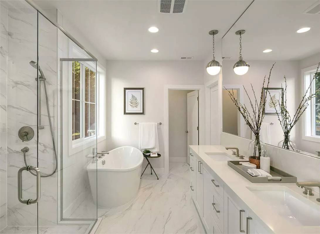 Primary bathroom with a dual sink vanity, a freestanding tub, and a walk-in shower with a glass hinged door.