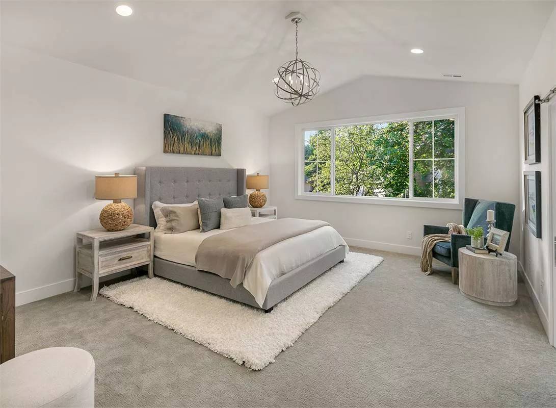 Primary bedroom with tufted bed, a wingback chair, and a spherical chandelier hanging from the vaulted ceiling.