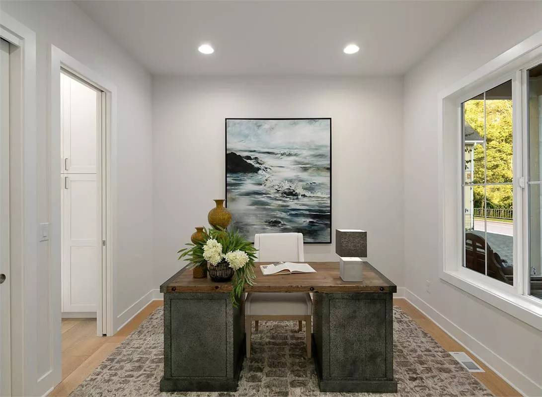 Home office with a rustic desk and an upholstered chair over a distressed area rug.