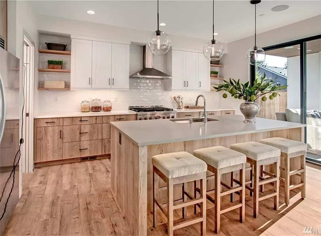 Kitchen with white and wooden cabinets, modern appliances, and a breakfast island with seating for four.