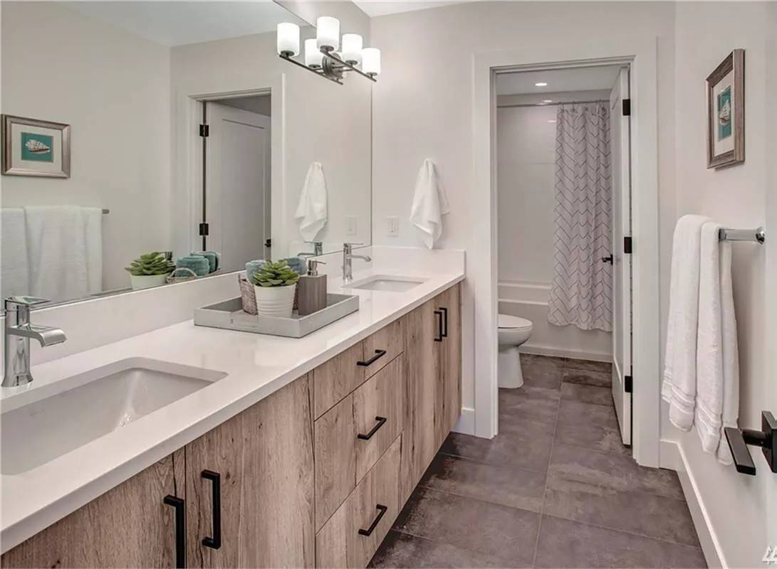 Bathroom with a dual sink vanity and a toilet room.