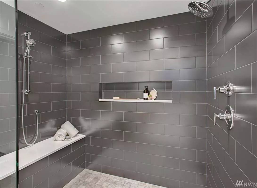 Primary shower with chrome fixtures and a tiled bench.