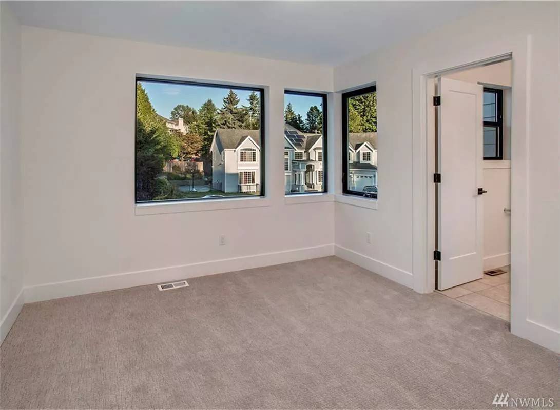 Bedroom with a carpeted floor and picture windows.