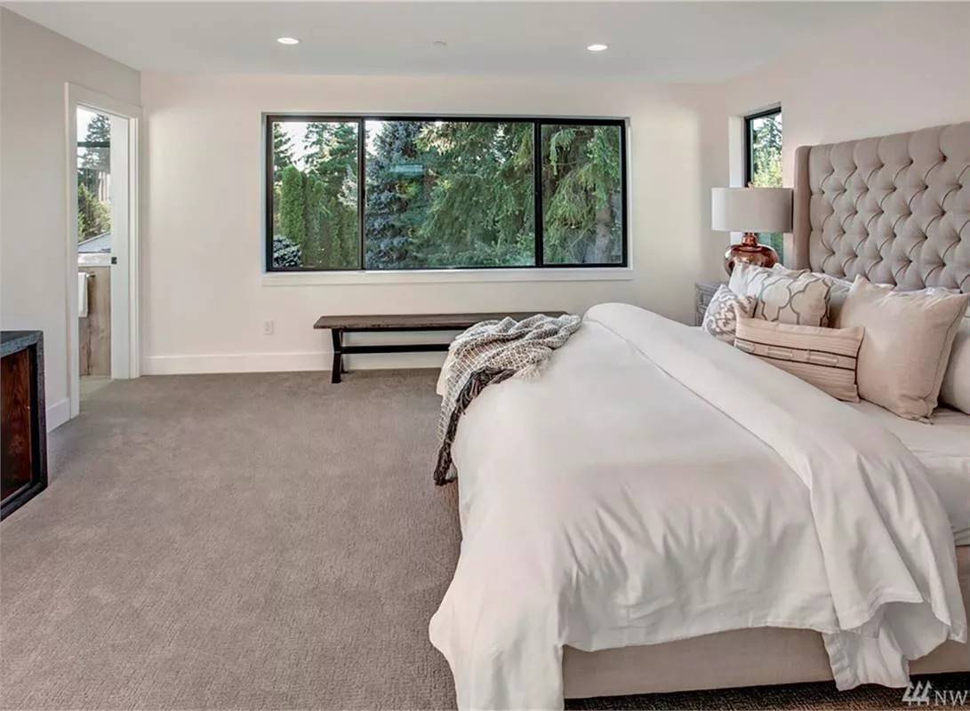 Primary bedroom with a tufted bed and a wooden bench under the sliding windows.