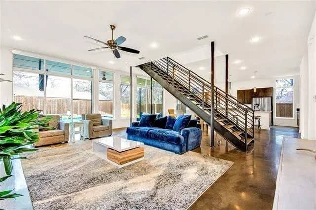Family room with a velvet sofa, a modern coffee table, and a wall of windows flooding the area with natural light.