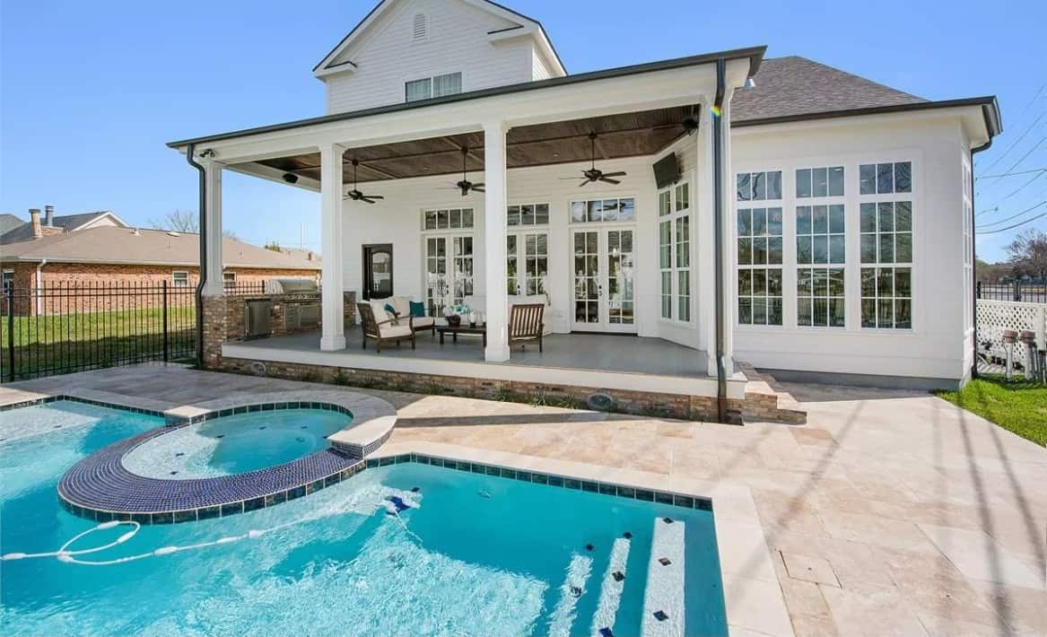 Rear view with a covered porch and a swimming pool integrated with a hot tub.