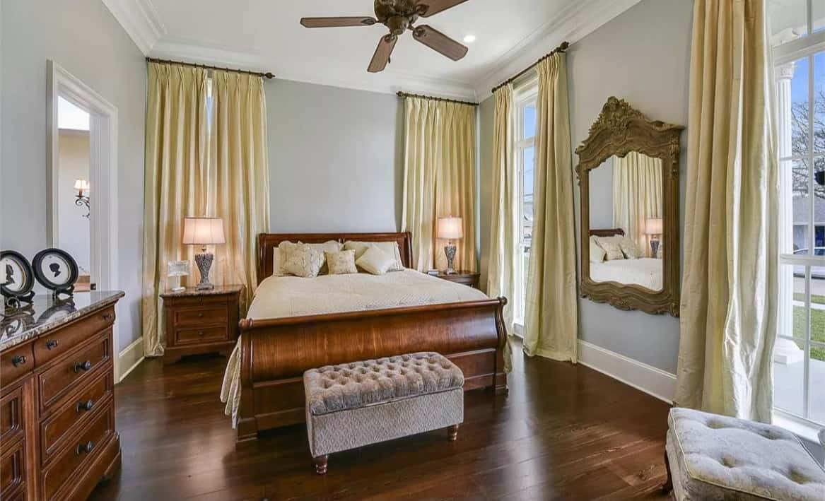Primary bedroom with a decorative mirror and wooden furnishings that blend in with the hardwood floor.