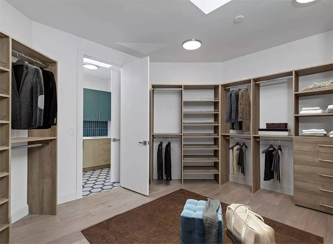 Primary walk-in closet with wooden built-ins that match the hardwood flooring.