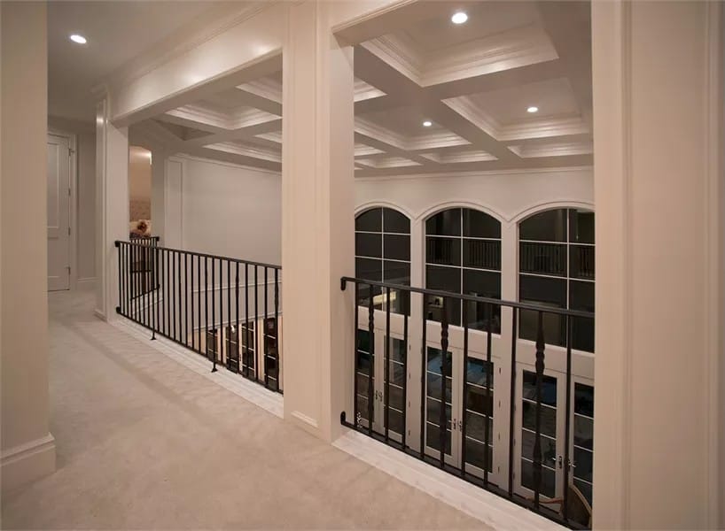Balcony with a carpeted floor and wrought iron railings overlooking the great room below.
